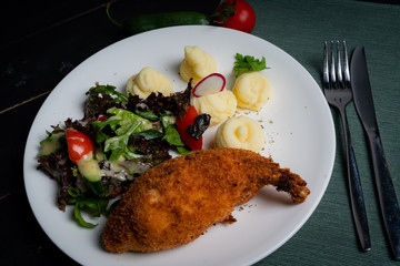 Chicken Kiev with vegetables and mashed potatoes on a white plate. 