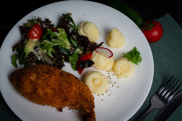 Chicken Kiev with vegetables and mashed potatoes on a white plate. 
