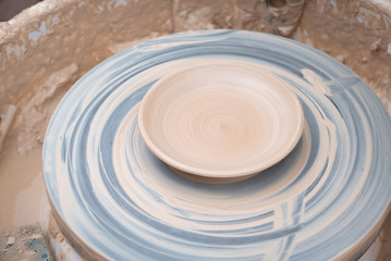 Fototapeta na wymiar Clay plate rotating on the pottery wheel