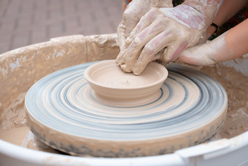 Hands forming clay on the pottery wheel