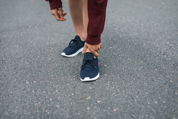 Painful running injury. Detail of runner holding her ankle.