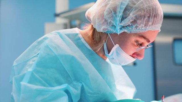 Female surgeon in operation room with reflection in glasses. blue light operating room, a rhinoplasty operation to improve the aesthetics of the nose. Medetsina, plastic surgery.