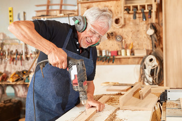 Schreiner Meister arbeitet mit der Bohrmaschine