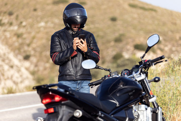 Man biker talking on the phone to the insurance of his motorcycle after having suffered a breakdown on the road. © nenetus