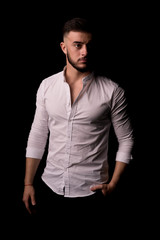 Portrait of stylish handsome young man with bristle standing indoors. Man wearing white shirt.