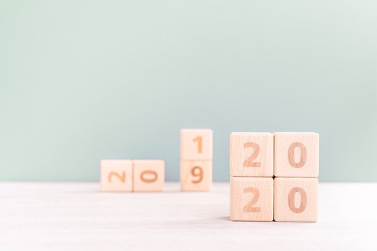 Abstract 2020, 2019 New year target plan design concept - wood blocks cubes on wooden table and pastel green background, close up, blank copy space.