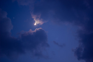 The photos of the moon in the night sky covered with clouds.