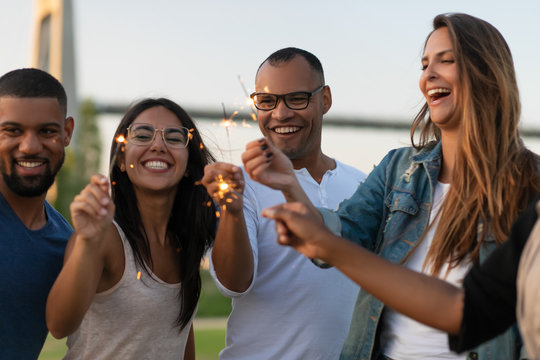 Front View Of Happy People Standing With Bengal Lights. Smiling Friends Spending Time Together Outdoor. Concept Of Celebration