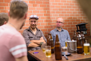 Group of men outdoors talking and drinking beer