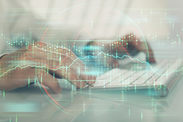 Double exposure of graph with man typing on computer in office on background. Concept of hard work.