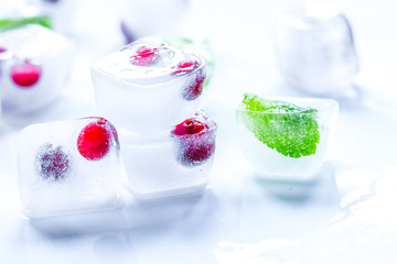 Fototapeta na wymiar ice cubes with red berries and mint white background