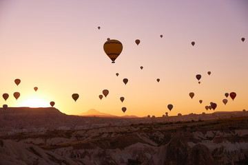 sunrise photo in Cappadocia with air balloons in the sky over sandy hills