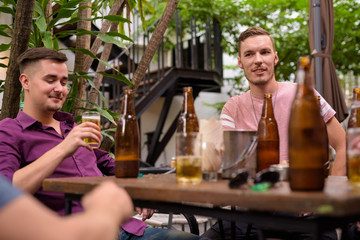 Happy men smiling while drinking beer outdoors