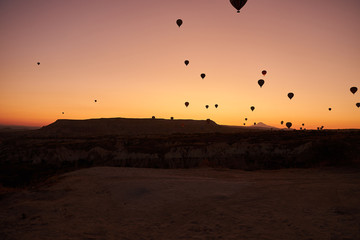 sunrise photo in Cappadocia with air balloons in the sky over sandy hills
