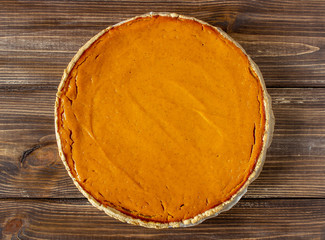 Pumpkin pie on a wooden background. Traditional recipe.