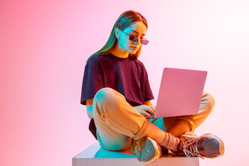 Modern Girl with laptop, tablet computer. Free creativity. A young blogger makes a Home office. Colored Neon light and background. - obrazy, fototapety, plakaty