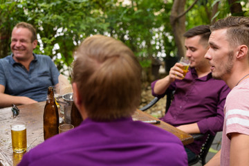 Group of men outdoors sitting and drinking beer