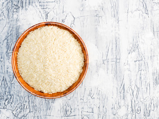 Basmati rice in a bamboo bowl on white concrete background