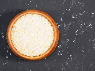 Basmati rice in a wooden bowl on black concrete background