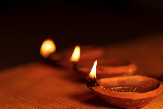Diwali Festival Of Lights. Stock photo of Diwali diya or clay oil lamp lit during the festival of lights in India. Dark moody background image of diyas for Diwali greeting card, religious tradition.