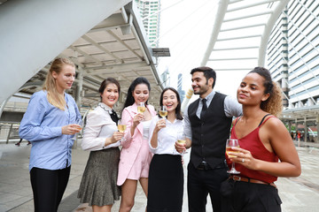 Successful multiethnic business people are clinking glasses of champagne with smiling while celebrating outdoor