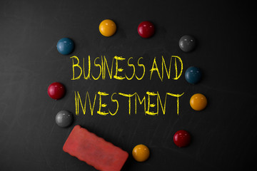 Word writing text Business And Investment. Business photo showcasing putting your money in field to increase them Round Flat shape stones with one eraser stick to old chalk black board