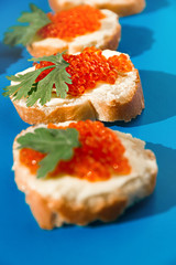 orange fish caviar lies in sandwich on white loaf with butter and parsley leaf, focus sandwich in the middle