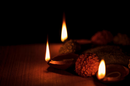 Three Decorative Burning Diya With Marigold Flowers. Diya lamps lit during diwali celebration with natural moody lighting and selective focused. Background image concept for religious tradition. 