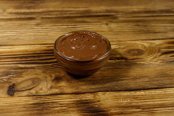 Glass bowl with delicious chocolate hazelnut spread on wooden table