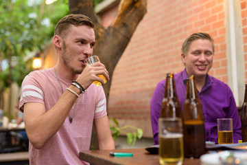 Happy man talking and drinking beer with friends