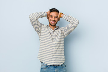 Fototapeta premium Young handsome filipino man laughs joyfully keeping hands on head. Happiness concept.