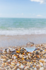 Glass round ball on the beach reflects the sea in summer