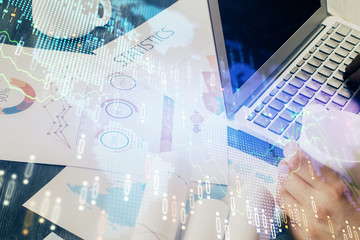 Double exposure of businessman's hands with laptop and stock market graph background. Concept of research and trading.