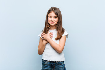 Fototapeta premium Cute girl has friendly expression, pressing palm to chest. Love concept.