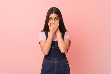 Young pretty arab woman wearing a jeans dungaree shocked covering mouth with hands.