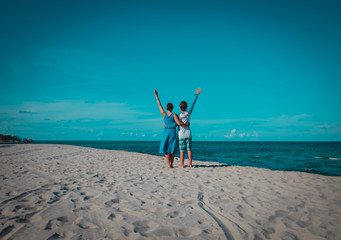 happy loving couple hands up on tropical beach