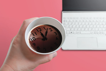 Coffee time on the desk. Coffee and clock reflected on the surface....