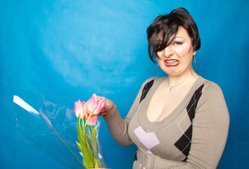 disgruntled woman with a bouquet of flowers emotionally shows hatred and disgust for cut flowers....