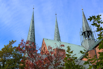 roof, towers and ridge turret of the luebeck cathedral, detail of the historic brick church against a blue sky with feather clouds, copy space