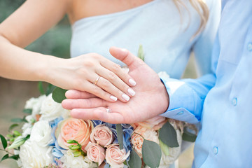 Groom wears bride a wedding ring Bride hand holds a beautiful wedding bouquet