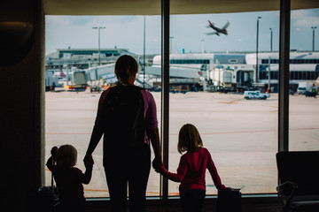 mother with kids and luggage looking at planes in airport