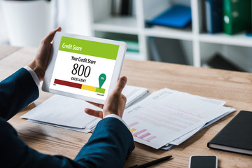 cropped view of man holding digital tablet with numbers and lettering near charts and graphs