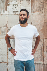 Fototapeta premium Handsome hipster man with beard wearing white blank t-shirt with space for your logo or design. white t shirt mockup.