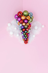Christmas tree made of ball decoration on pink background.