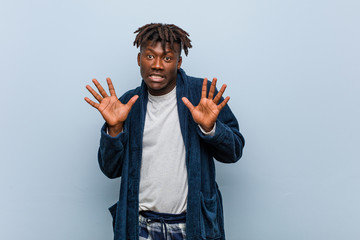 Young african black man wearing pajama rejecting someone showing a gesture of disgust.