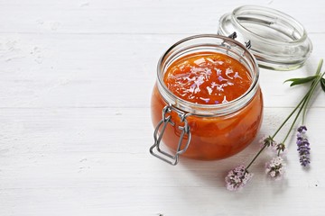 Apricot lavender marmalade in a glass jar on a rustic wooden table