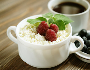 Russian cottage cheese with berry and mint, blueberries and coffee on wooden table.