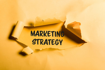 tattered paper with marketing strategy lettering and rolled edges on orange