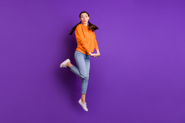 Fototapeta na wymiar Full length photo of funny funky youth girl jump feel carefree childish moving wear modern teenager clothes denim jeans white sneakers isolated over violet purple color background
