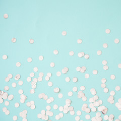 Silver foil confetti on light blue background. Festive, party or holiday glowing backdrop. Flat lay, top view.